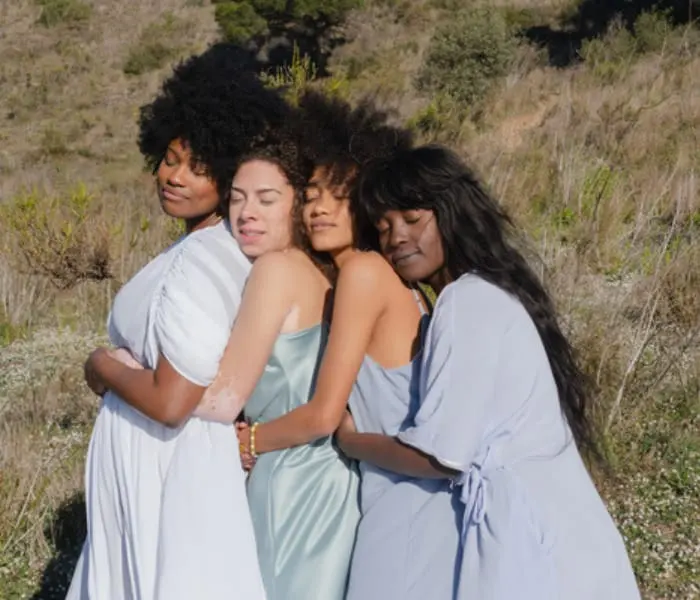 Quatre femmes enlacées dans la nature, en signe de soutien